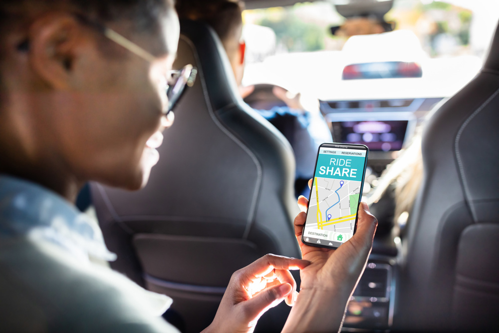 African woman using car sharing app while sitting in car