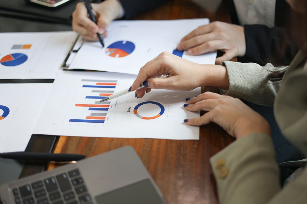 Business professionals reviewing financial documents contain data of pie charts and graphs