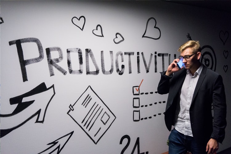 A man holding smartphone and looking at productivity wall decor