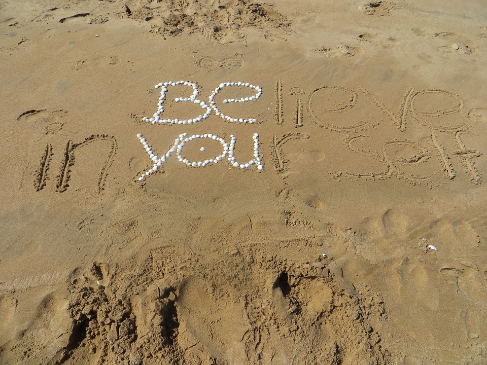 “believe in yourself” written on sand