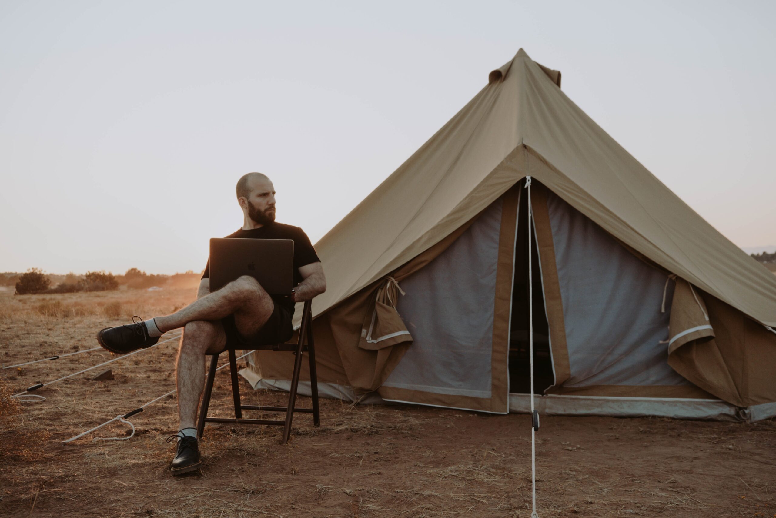 man-relaxing-with-laptop-near-tent