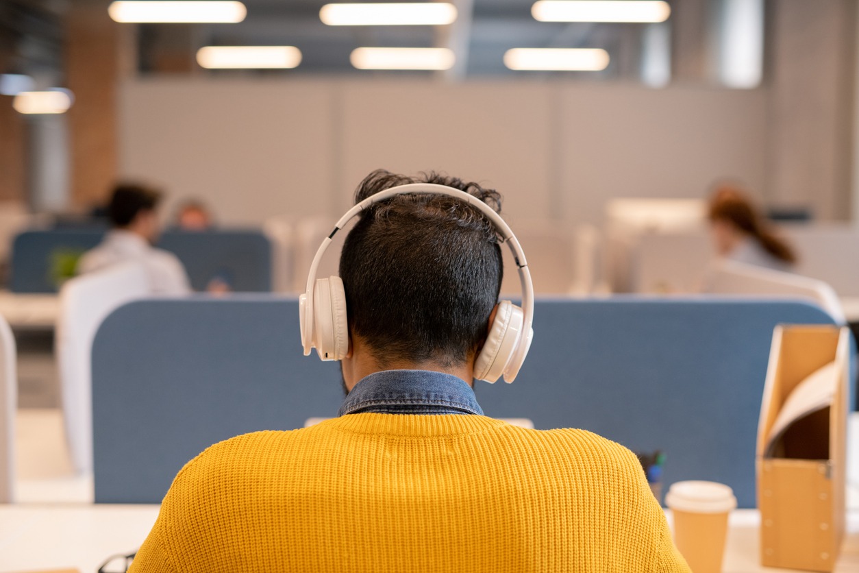 a rear view of a man wearing headphones in the office