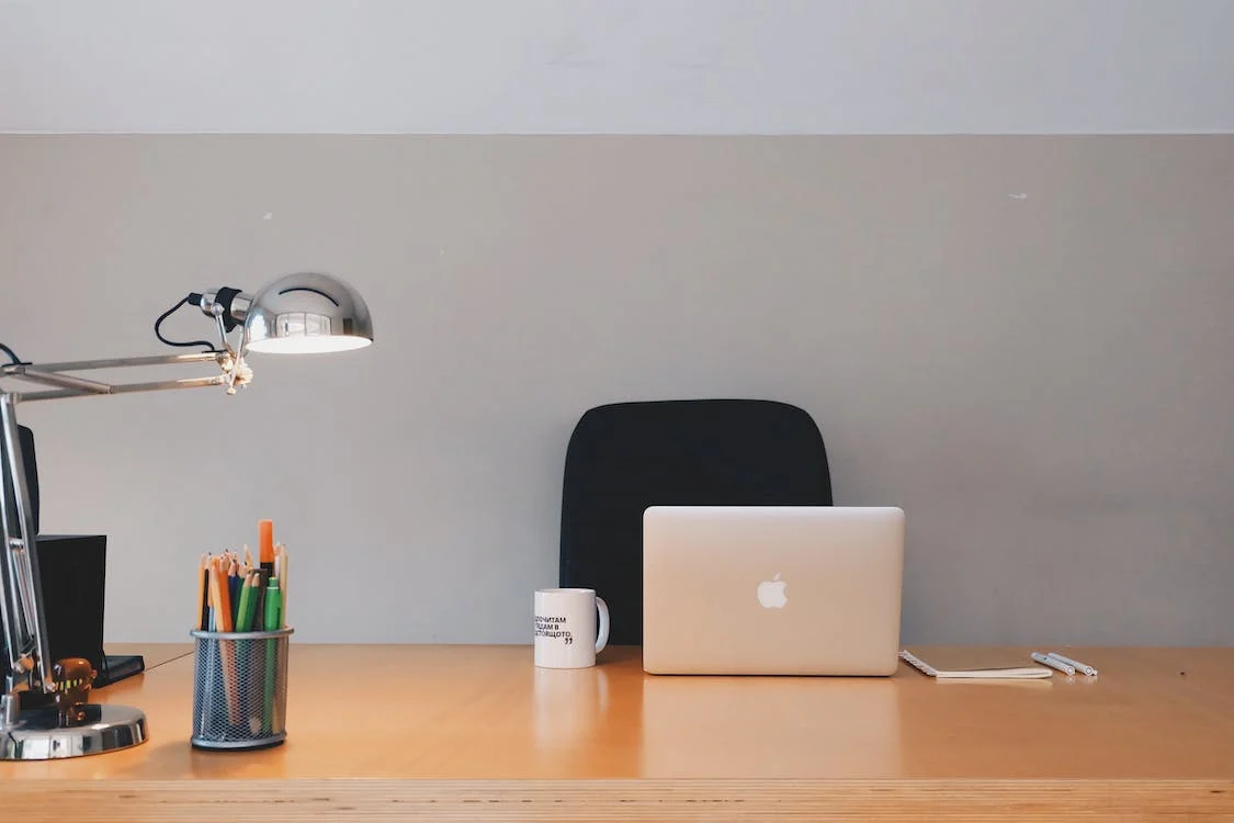 A-desk-with-a-laptop-lamp-and-other-items-on-it