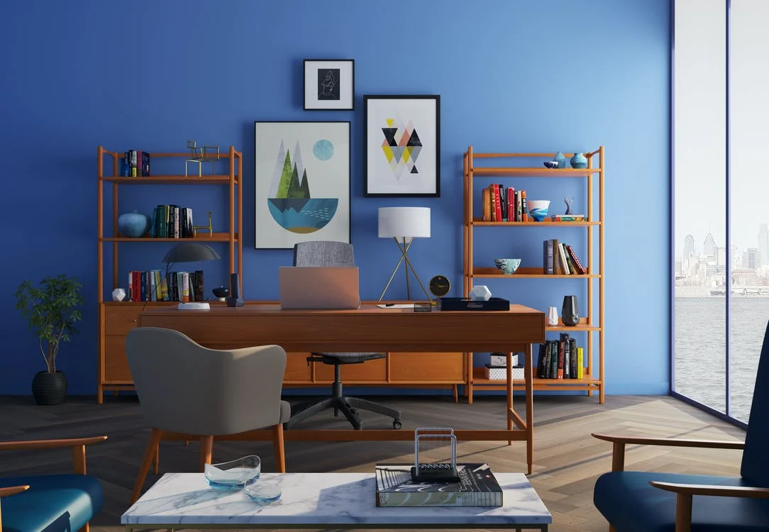 An-office-with-a-desk-shelving-artwork-and-visitor-chair