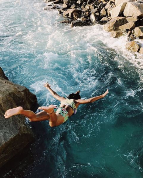 a-woman-in-a-bikini-jumping-off-a-cliff